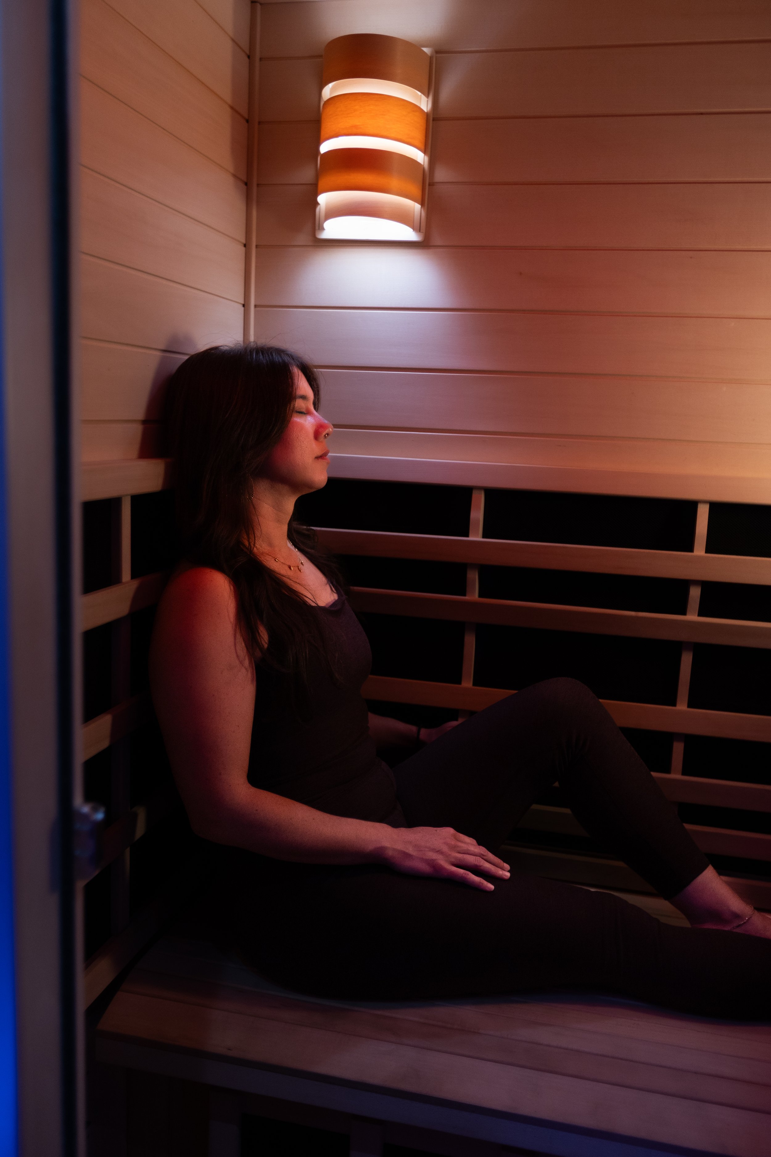 A person seated inside the wood-lined infrared sauna at Union