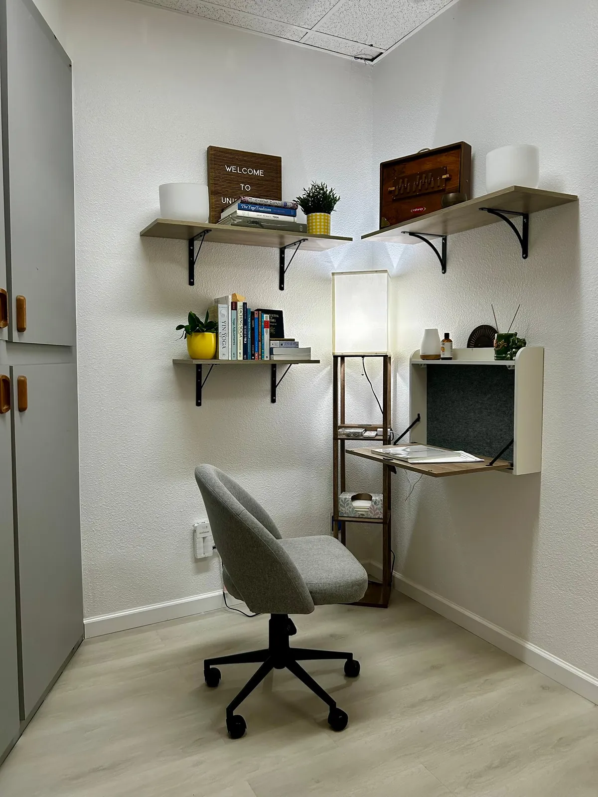 Gray swivel chair beside a fold-down desk, lamp and wooden shelves at Union Yoga.