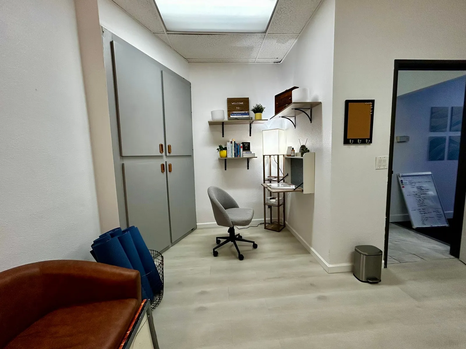 Wide view of the furnished nook at Union Yoga, with a gray chair, cabinets and wall shelves.